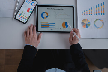 Businesswoman pointing at sales performance chart displayed on digital tablet with stylus, using...