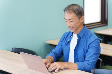 ノートパソコンを使うシニア男性