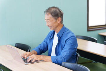 ノートパソコンを使うシニア男性