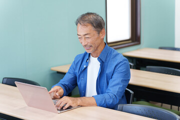 ノートパソコンを使うシニア男性