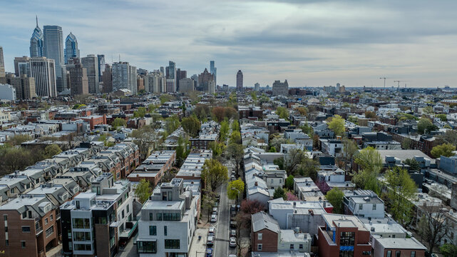 Aerial view of rows of houses leading to a skyline punctuated by skyscrapers, creating a striking contrast between residential calm and urban energy, Philadelphia, Pennsylvania, United States.
