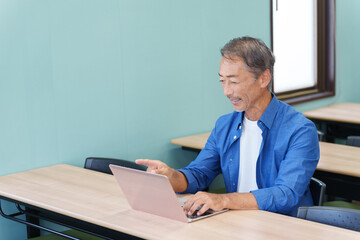 ノートパソコンを使うシニア男性