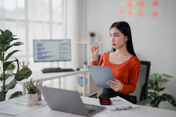 Young Asian businesswoman working from home using tablet and thinking about project strategy, she's...