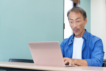 ノートパソコンを使い驚くシニア男性