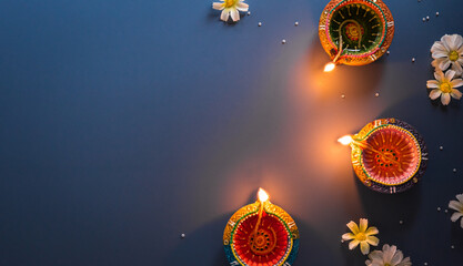 Happy Diwali - Clay Diya lamps lit during Diwali, Hindu festival of lights celebration. Colorful traditional oil lamp diya on blue background