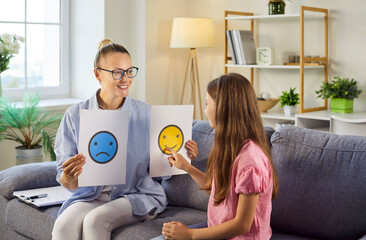 Therapy session with psychologist and child discussing emotions. Counselor uses emotion cards to help the girl name feelings and build communication. Mental health and emotional support concept.