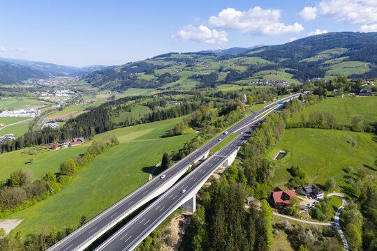 Aerial view of the highway cutting through the verdant Lavanttal valley, a ribbon of grey against the vibrant green landscape, Wolfsberg, Carinthia, Austria.