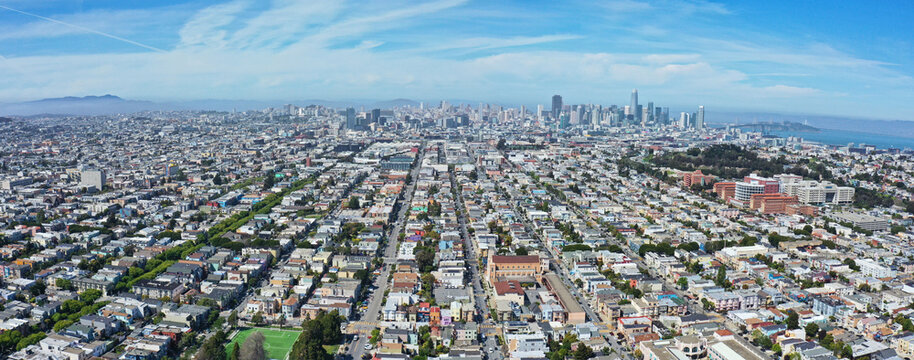 Aerial view of a sprawling cityscape where rows of houses lead to towering skyscrapers under a vast sky, San Francisco, California, USA.