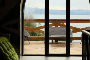 Scenic view of Bukhtarma Reservoir and mountains from the window of a resort hotel with wicker...