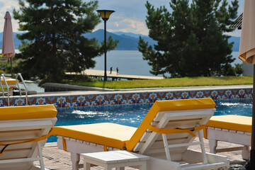 Yellow loungers by the pool at a resort on Bukhtarma Reservoir with mountain view, calm early autumn holiday vibe