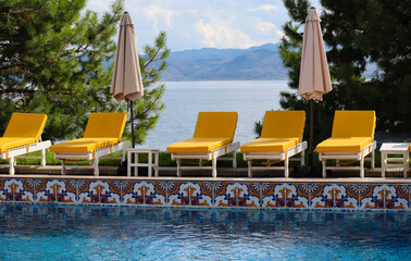 Yellow loungers by the pool at a resort on Bukhtarma Reservoir with mountain view, calm early autumn holiday vibe