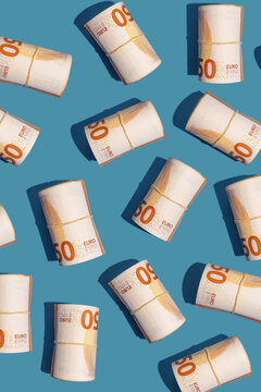 Fifty euro notes rolled and arranged on blue background with copy space