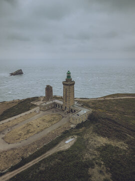 Aerial view of the imposing Cap Fr&Atilde;&copy;hel lighthouse stands proudly against the moody, grey Atlantic, its stone walls weathered by time and sea spray, Pl&Atilde;&copy;venon, Bretagne, France.