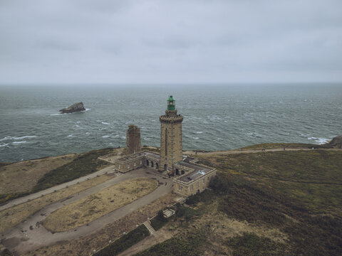 Aerial view of the majestic Cap Fr&Atilde;&copy;hel lighthouse standing tall against the turbulent sea, with the rugged coastline adding drama to the scene, Pl&Atilde;&copy;venon, Bretagne, France.