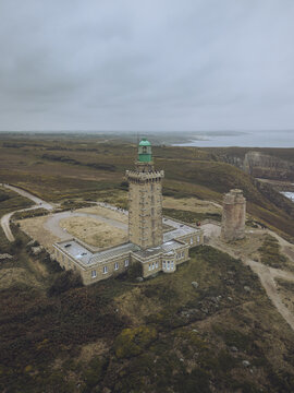 Aerial view of the Phare du Cap Fr&Atilde;&copy;hel lighthouse standing tall against the muted landscape, its green top contrasting with the somber sky, Pl&Atilde;&copy;venon, Bretagne, France.