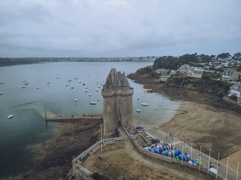 Aerial view of the imposing Tour Solidor standing guard where the Rance River meets the sea, its stone walls a stark contrast to the soft, sandy beach, Saint-Malo, Bretagne, France.