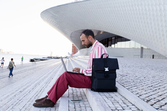 Person in red outfit working on laptop outdoors at Maat Lisbon