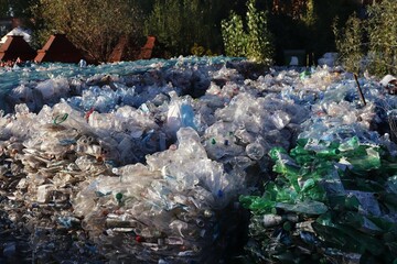 Mountains of compressed plastic bottles prepared for recycling — a symbol of the modern...