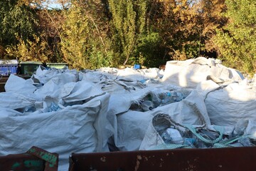 Garbage containers and large waste bags at a collection site — symbol of disposal, recycling, and...