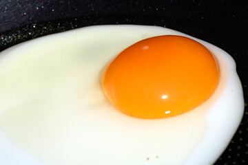 Close up of a fried egg in a pan being cooked