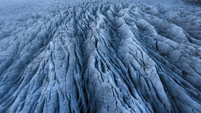Aerial view of the glacier's icy surface, sculpted by time and elements, reveals a mesmerizing pattern of ridges and valleys stretching towards the horizon, Sveitarf&Atilde;&copy;lagi&Atilde;&deg; Hornafj&Atilde;&para;r&Atilde;&deg;ur, Iceland.