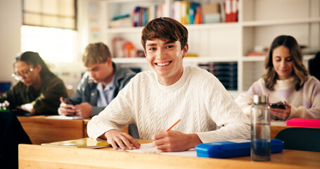 Smile, writing and portrait of teenager in classroom for learning, education or development. Happy, books and face of boy with studying at high school for test, exam or assignment on campus.