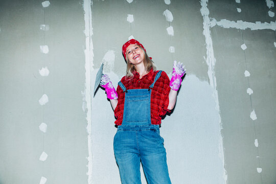 Confident woman plastering drywall during home renovation indoors