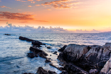 beautiful sea sunset among rocks and blue water vawes and amazing colorful cloudy evening sky on...