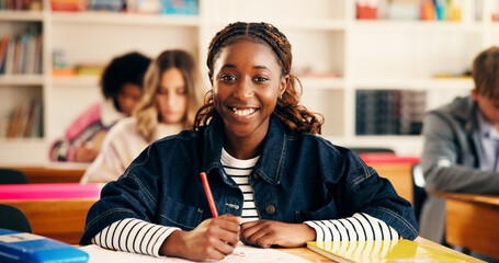 Happy, writing and portrait of teenager in classroom for learning, education or development. Smile, books and girl student with studying at high school for test, exam or assignment on campus.