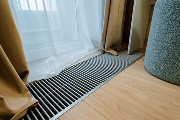 A contemporary interior view that showcases a radiator vent alongside elegant drapery, positioned...