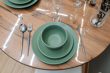 An Elegant Green Dinner Set on a rustic Wooden Table, showcasing a stylish Dining Arrangement ideal for gatherings or special occasions, complete with exquisite glassware