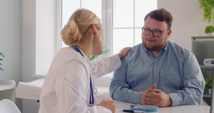 Doctor and fat patient in consultation at healthcare clinic, confirming appointment, giving wellness advice, obesity counseling and support. Physician and overweight man build trust through empathy.