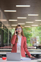 Fototapeta premium Asian businesswoman working on financial market research using laptop and digital tablet, stressed about digital investment in office.