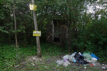Garbage in forest with added information on trees - prohibition of throwing the litter about.