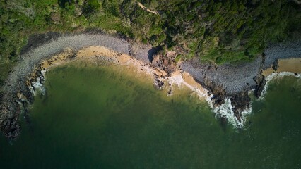 Aerial view of a rocky coastline with lush greenery.
