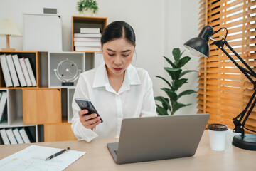 stressed woman working with smartphone and laptop computer at home office