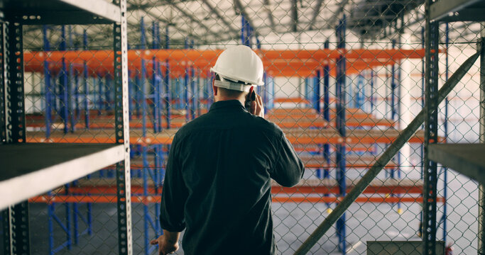 Logistics, business or man in warehouse with phone call, distribution or shipping of package. Communication, back or supervisor in storage facility with tech, inventory or plan for import process - Powered by Adobe