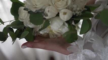 bridal bouquet of white roses held gently with greenery detail