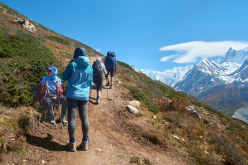 Group of hikers rest on trail high in mountains during Annapurna Circuit trek in Nepal.
