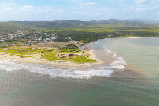 Aerial view of the shoreline where the river meets the ocean, contrasting sand and water hues under a vast sky, Puerto Colombia, Atlantico, Colombia.