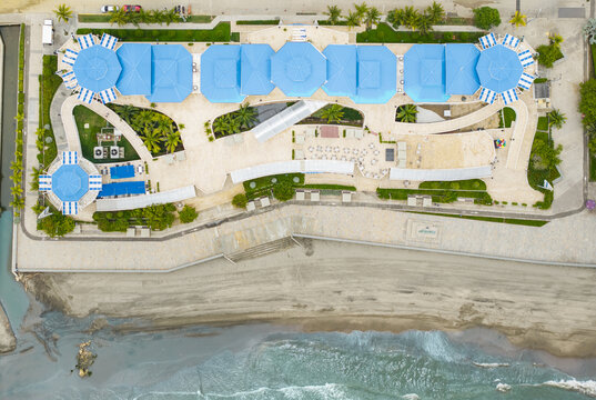 Aerial view of blue-roofed buildings meet the sandy beach and turquoise waters, a coastal haven of architectural harmony, Puerto Colombia, Atlantico, Colombia.