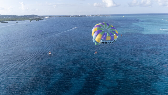 Aerial view of a parasail soaring above the turquoise waters, with boats leaving white wakes, against the backdrop of a distant coastline, San Andr&Atilde;&copy;s, San Andres and Providencia, Colombia.