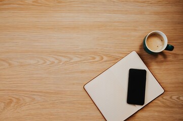 Phone on Notebook with Coffee on Wood