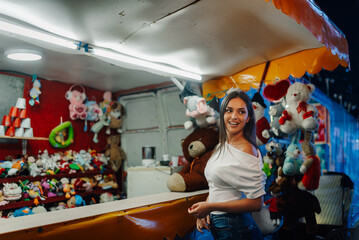Young woman playing games at amusement park plush toys booth