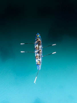 Aerial view of a blue rowing boat slicing through the turquoise waters, creating a mesmerizing contrast against the dark depths below, Perth, Western Australia, Australia.