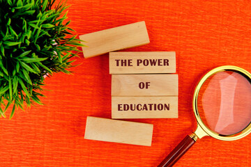 Concept words THE POWER OF EDUCATION assembled from wooden blocks in composition with magnifying...