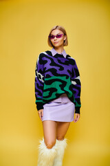 Stylish blonde woman showcases trendy outfit in vibrant studio setting