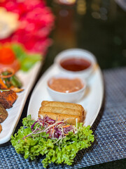 Hospitality and sharing symbolized by crispy spring rolls with colorful garnish and sauces, representing celebration, togetherness, and lifestyle dining experience.