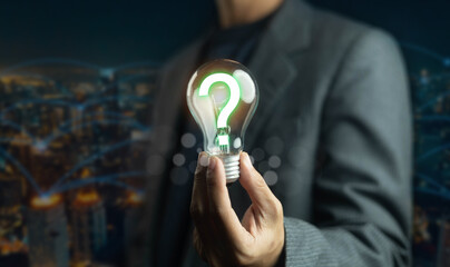 Businessman holding glowing light bulb with question mark symbol, representing innovation,...