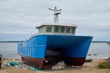 An Abandoned Blue Fishing Boat Resting on the Serene Shoreline, Evoking a Sense of Nostalgia
